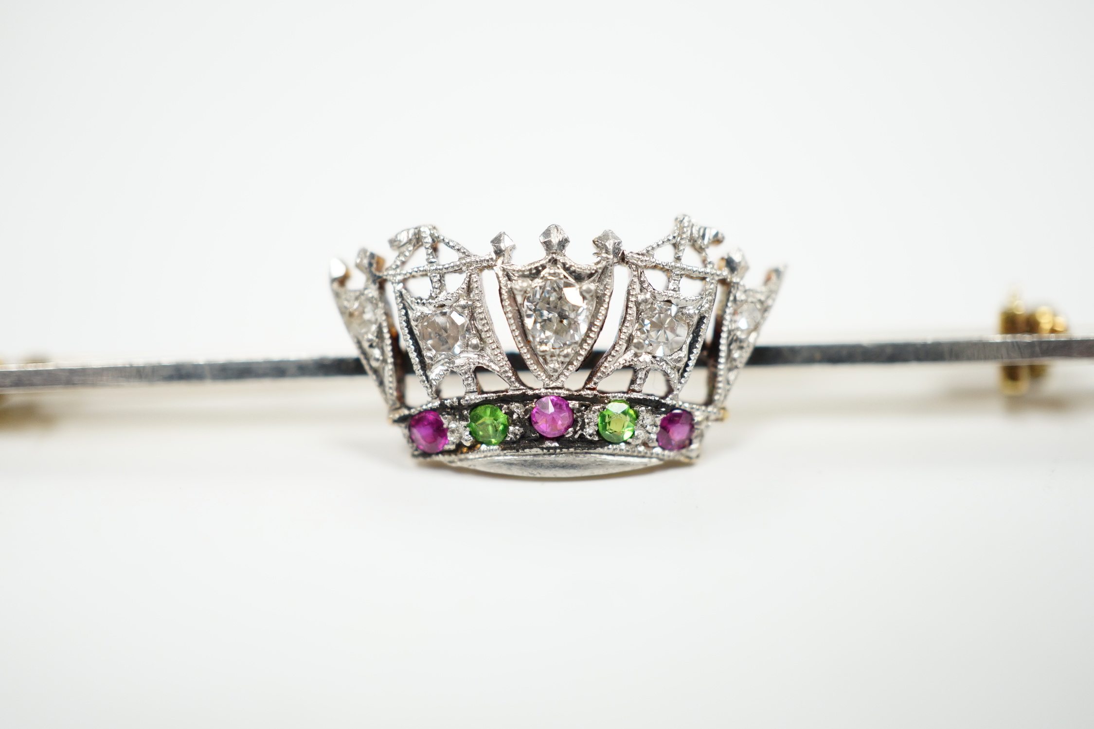 An early 20th century, 15ct and plat. ruby, green garnet and diamond set coronet bar brooch, 50mm, gross weight 3.4 grams.